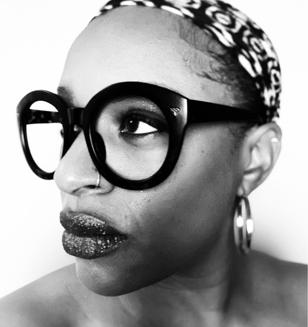 Syntyché Francella, a black woman with big thick glasses and bold lips, looking off into the distance.